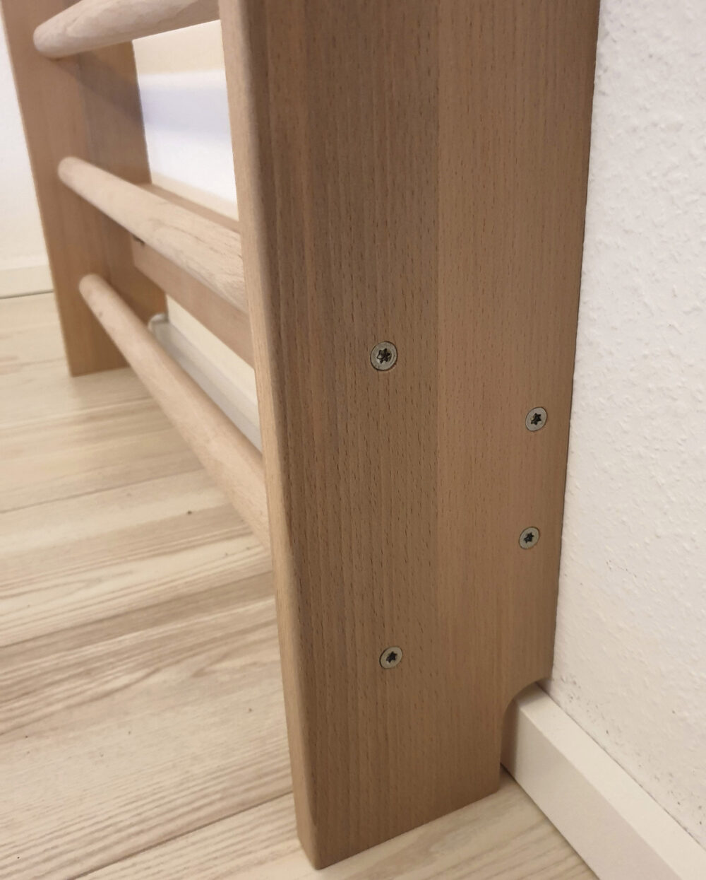 Detailaufnahme der selbstgebauten Sprossenwand mit versenkten Schrauben und Aussparung für die Sockelleiste